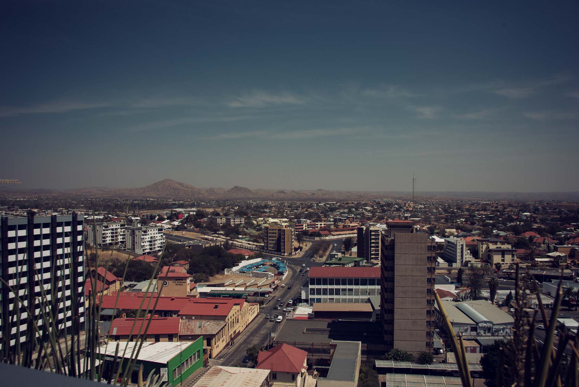 Namibia Windhoek | Kenzan Travel City skyline with low-rise and mid-rise buildings stretching to the horizon, mountains in the distance under a clear blue sky